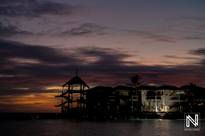 A Serene Sunset View Over the Water Highlighting a Beachfront Structure and Tropical Palms During Dusk by the Coast