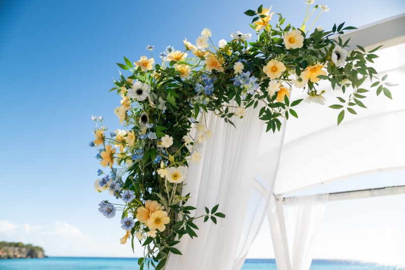 Wedding ceremony decoration with floral arch overlooking Playa Porto Mari in Curacao during a sunny day, creating a romantic ambiance for couples