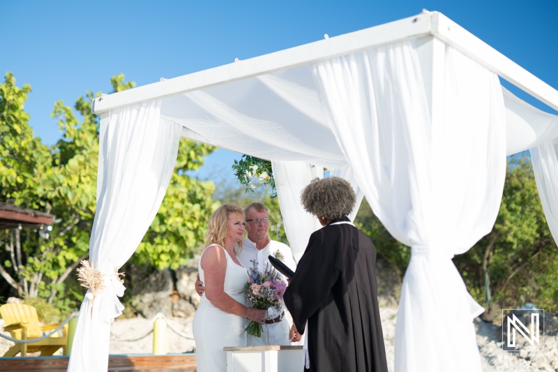 Wedding ceremony at Playa Porto Mari in Curacao under a bright blue sky with a beautiful floral arrangement