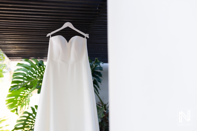Elegant wedding dress hanging in lush setting of Curacao, showcasing special moment before tropical celebration