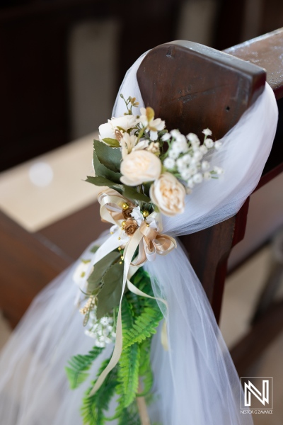 Beautiful floral decoration on a pew for a wedding ceremony in Curacao with soft fabrics and natural accents