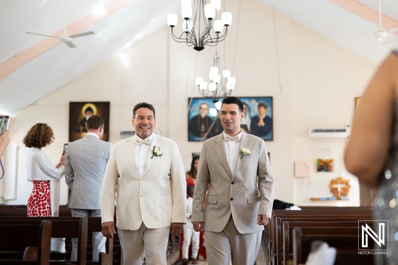 Wedding ceremony celebration in Curacao featuring grooms walking down the aisle with guests and family in attendance