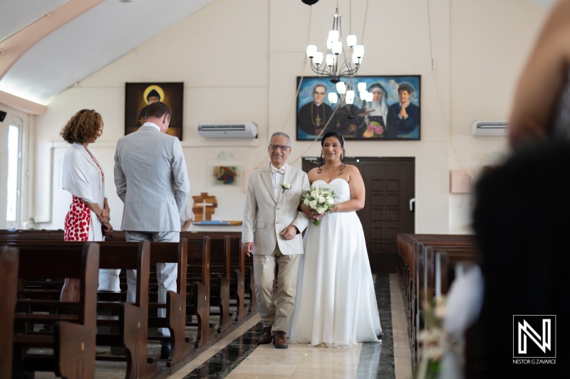 Wedding ceremony in Curacao featuring a bride walking down the aisle with her father in a charming church setting