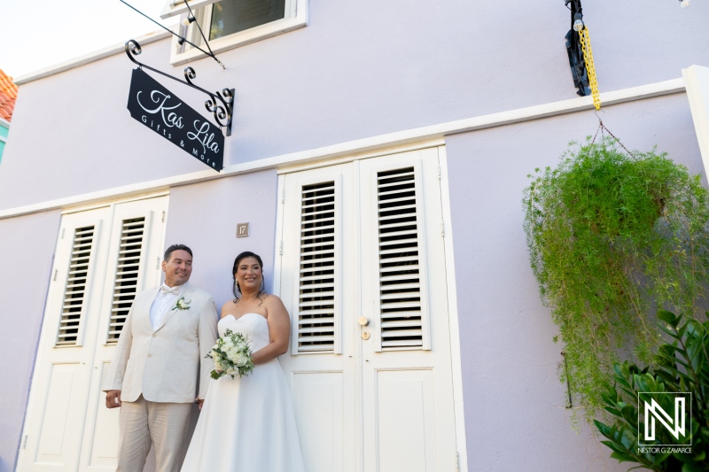 Couple celebrates their wedding in front of a beautiful pastel building in Curacao, capturing a joyful moment of love and happiness