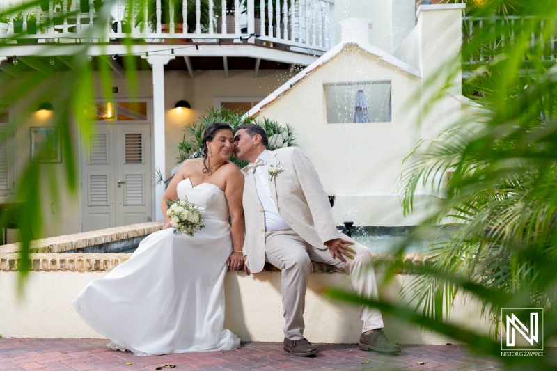 Couple celebrating their wedding at a picturesque venue in Curacao with lush greenery and a charming fountain backdrop