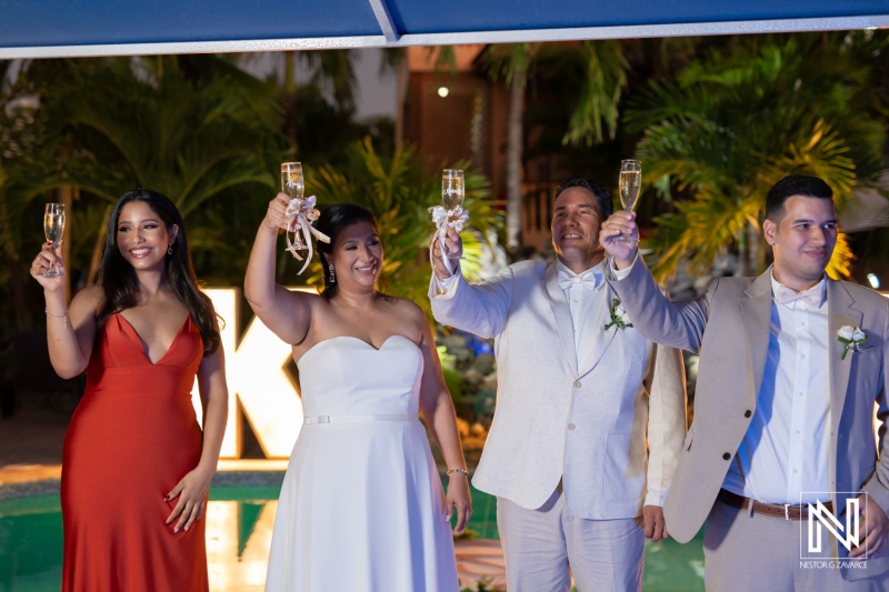 Wedding celebration in Curacao with guests toasting by the pool at a tropical venue during the evening