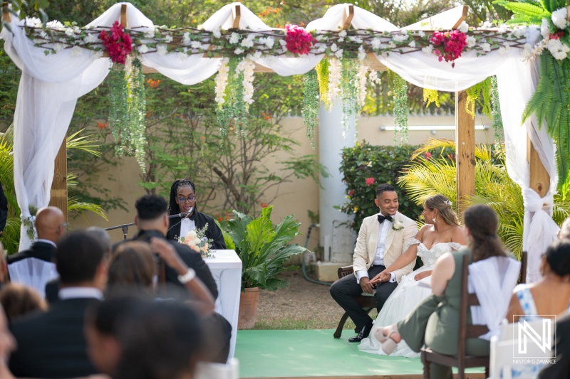 Beautiful wedding ceremony in Curacao featuring a joyful couple under an arch decorated with flowers, surrounded by loved ones