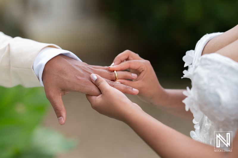 Couple exchanging wedding rings during a beautiful ceremony in Curacao surrounded by lush greenery and vibrant decorations