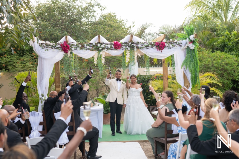 Couple celebrates wedding ceremony in Curacao surrounded by joyful guests in a beautiful outdoor setting