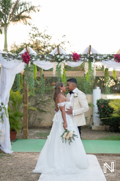 Couple exchanges vows at a romantic wedding ceremony in Curacao under a beautiful arch adorned with flowers