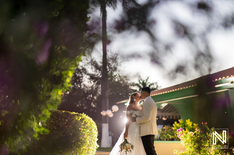 Couple celebrates their love during a romantic wedding ceremony in Curacao, surrounded by lush greenery and enchanting sunset light