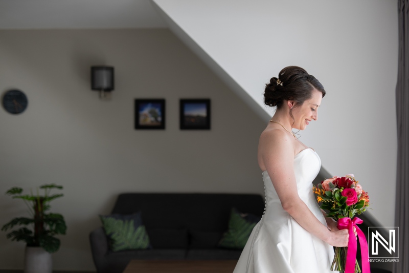 Beautiful bride prepares for wedding at Avila Beach Hotel in Curacao with vibrant bouquet and joyful demeanor