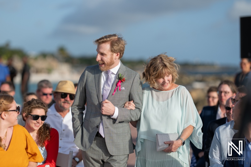 Groom walks down the aisle with his mother during a charming wedding ceremony at Avila Beach Hotel in Curacao