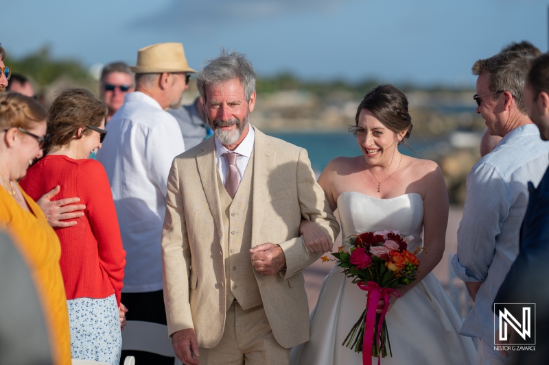 Joyful wedding ceremony at Avila Beach Hotel in Curacao with the bride and her father walking together