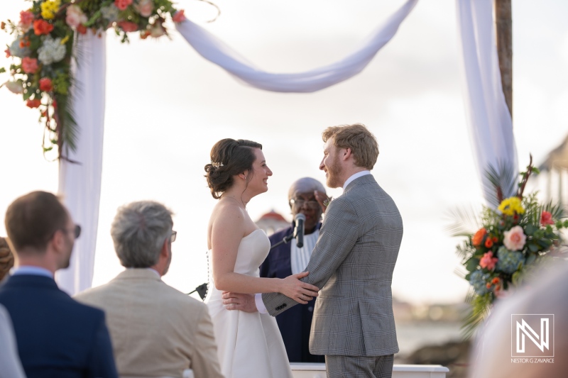 Couple exchanges vows during a beautiful wedding ceremony at Avila Beach Hotel in Curacao under a floral arch