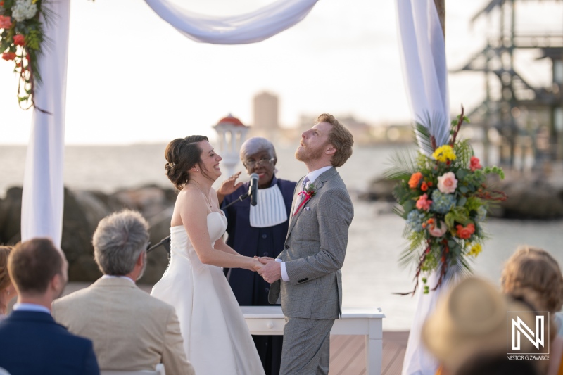 Couple exchanges vows during a romantic wedding ceremony at Avila Beach Hotel in Curacao under a beautiful sunset sky