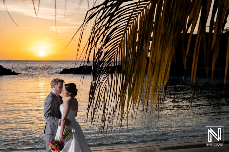 Couple celebrating their wedding at Avila Beach Hotel in Curacao during a stunning sunset by the calm ocean