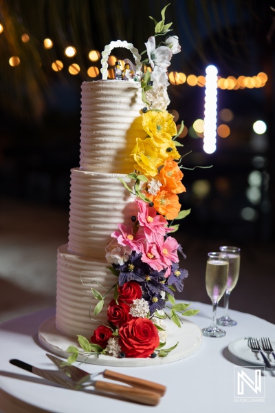 Beautiful wedding cake adorned with vibrant flowers at Avila Beach Hotel in Curacao during a romantic evening celebration