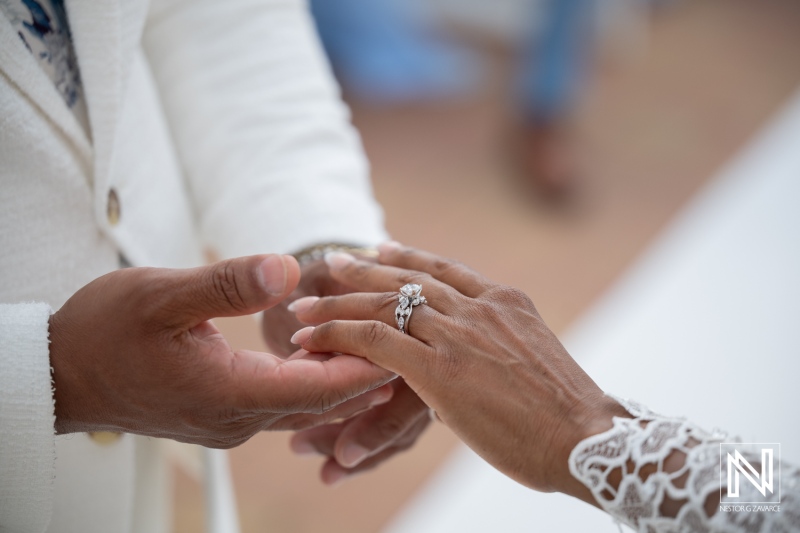 Couple exchanges rings during wedding ceremony at Avila Beach Hotel in Curacao under bright sky
