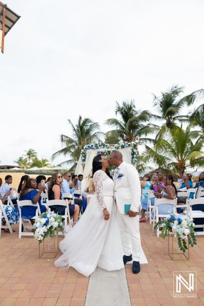 Couple exchanges vows during a wedding ceremony at Avila Beach Hotel in Curacao on a sunny day with palm trees and guests present