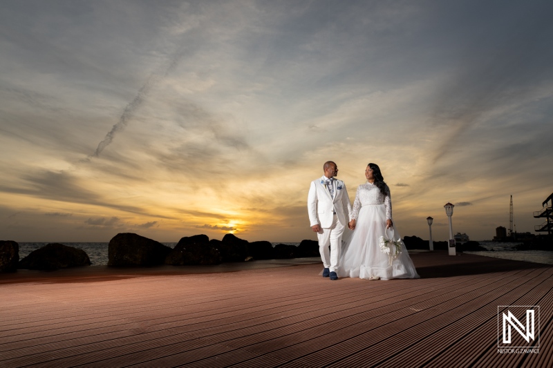 Couple walks together during wedding ceremony at Avila Beach Hotel in Curacao as the sun sets on the horizon