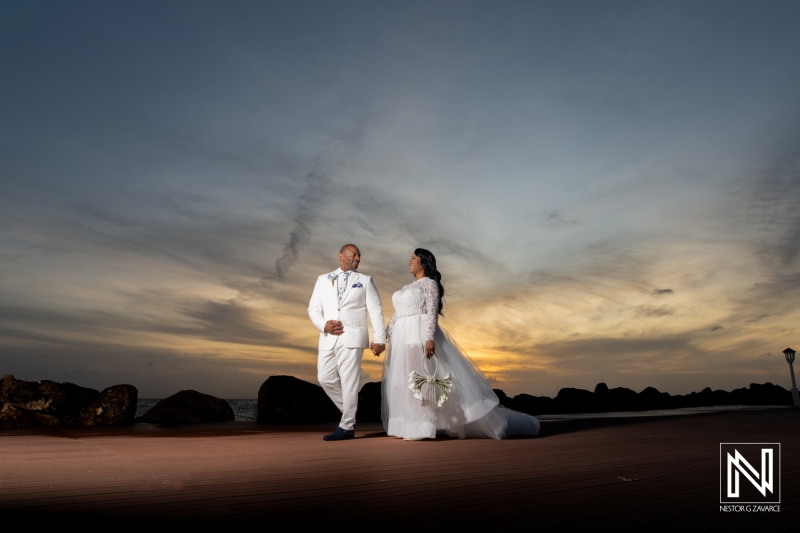 Couple walks hand in hand at their wedding ceremony at Avila Beach Hotel during sunset in Curacao