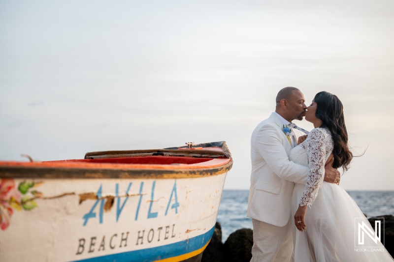 Couple shares a kiss while standing by the water at Avila Beach Hotel during their wedding ceremony in Curacao