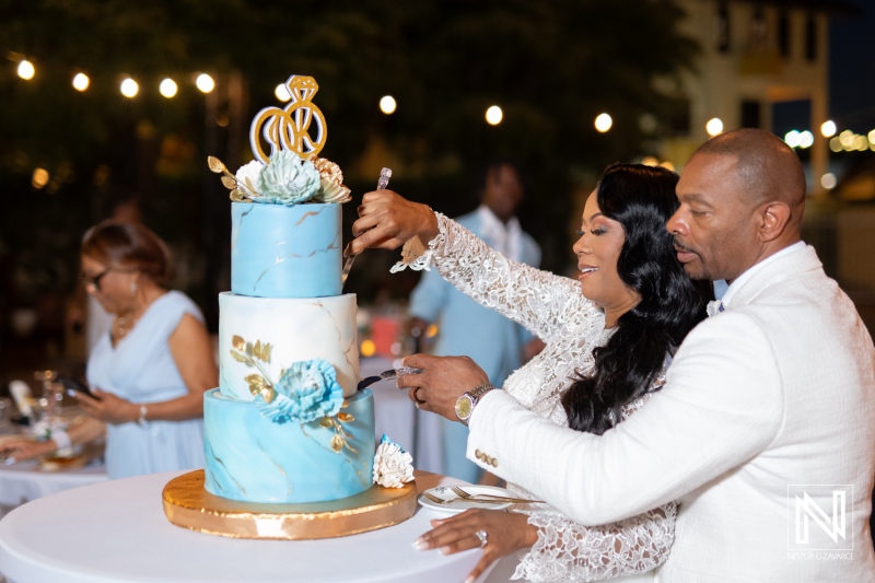 Couple cuts wedding cake at Avila Beach Hotel in Curacao during evening celebration with guests