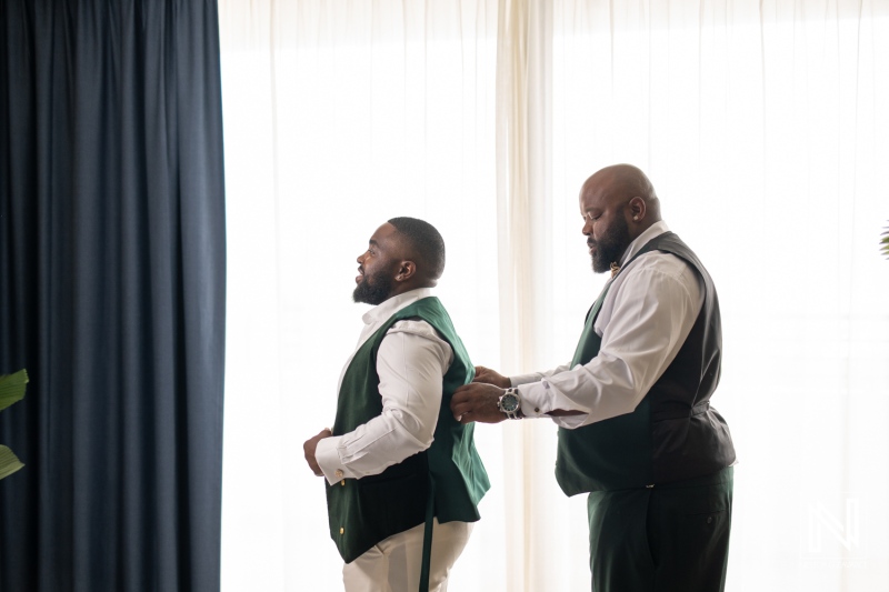 Groom getting ready for wedding ceremony at Mangrove Beach Corendon in Curacao with a friend assisting in the preparation