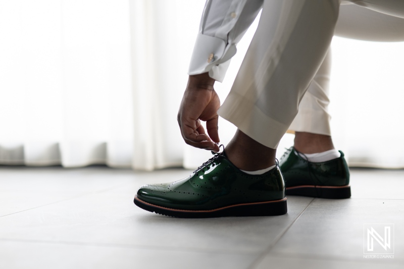 Elegant groom prepares for a wedding at Mangrove Beach Corendon in Curacao with stylish green shoes and tailored attire