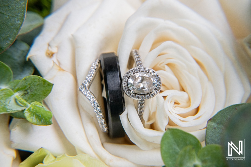 Wedding rings nestled among white roses at Mangrove Beach Corendon in Curacao, celebrating love and commitment in a picturesque setting