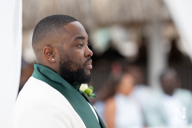 Groom stands proudly during wedding ceremony at Mangrove Beach Corendon in Curacao, celebrating love and commitment among friends and family