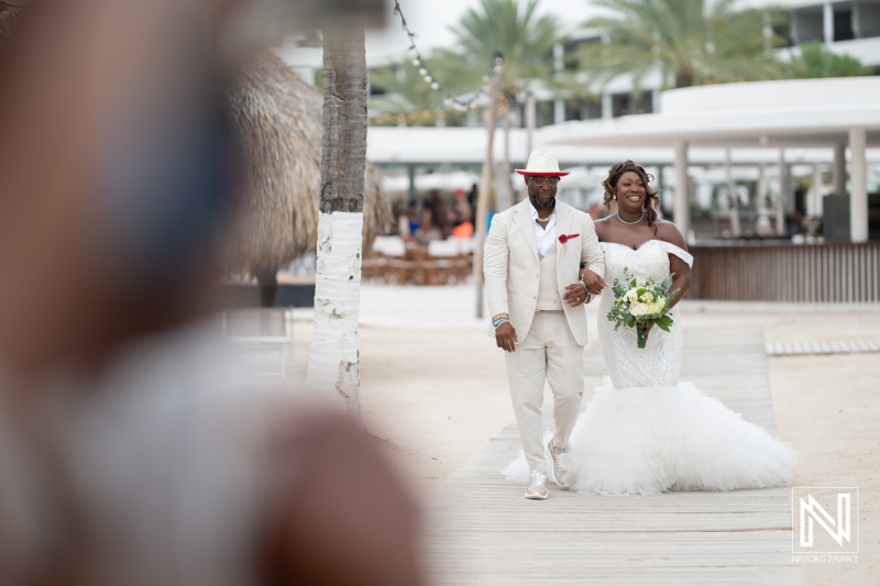 Wedding celebration at Mangrove Beach Corendon in Curacao features joyous couple walking along the beachside venue surrounded by palm trees