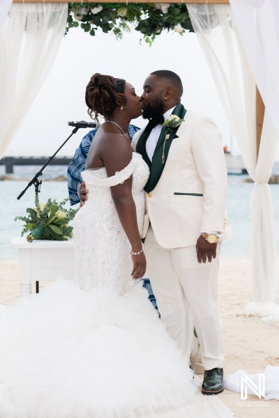 Couple shares a joyful kiss during their wedding ceremony at Mangrove Beach Corendon, Curacao, surrounded by nature and love