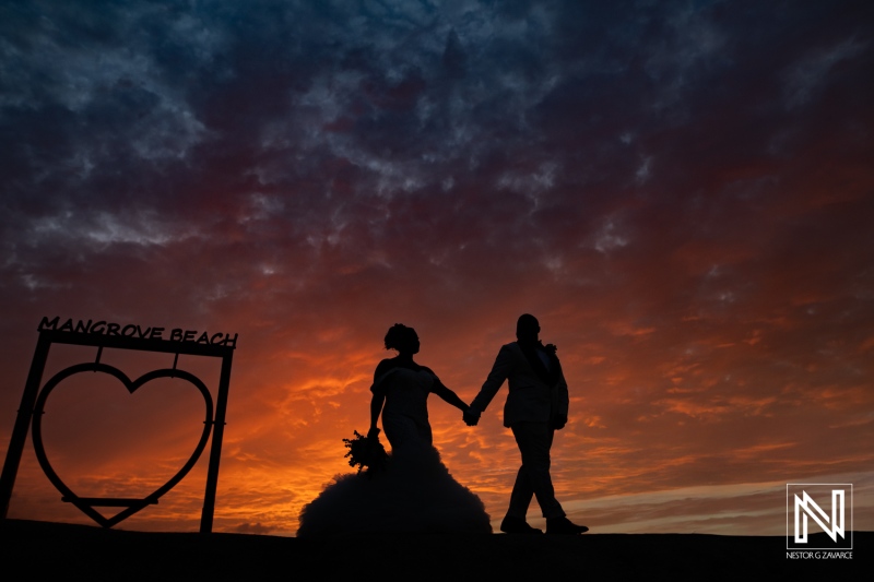 Couple walks hand in hand at sunset on the beach during a wedding celebration in Mangrove Beach Curacao