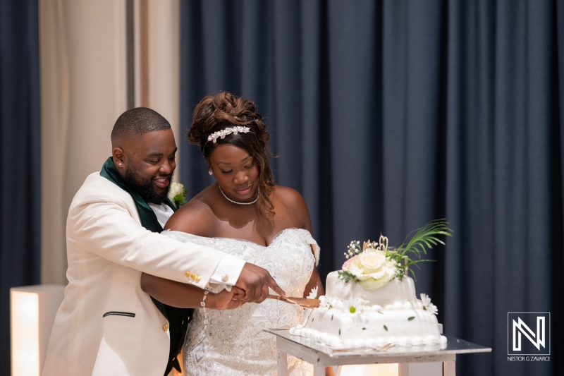 Couple celebrates their wedding at Mangrove Beach Corendon in Curacao, sharing a joyful cake-cutting moment among friends and family