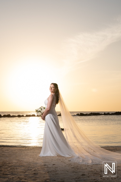 Stunning bride stands on the beach at sunset in Curacao celebrating her wedding at Sunscape Curacao Resort