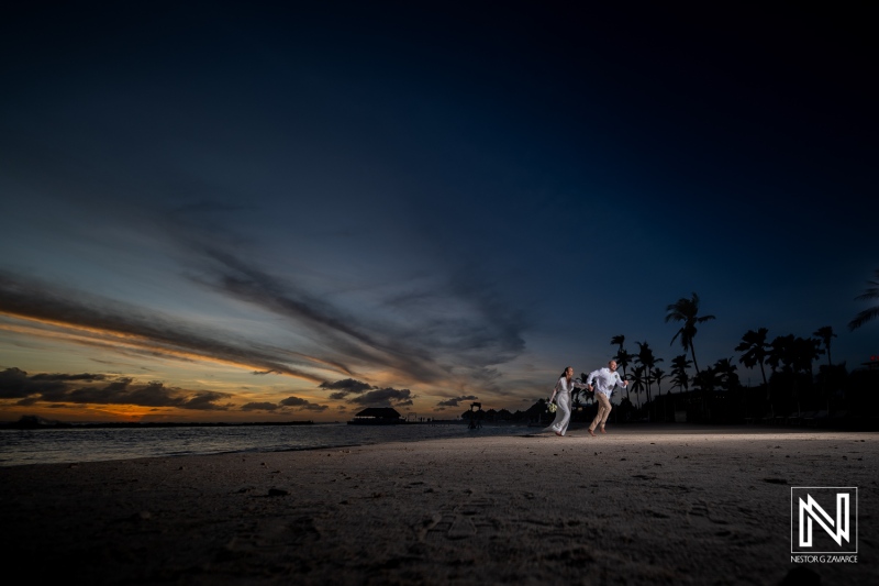 Couple joyfully running along Mangrove Beach in Curacao during a beautiful sunset wedding celebration