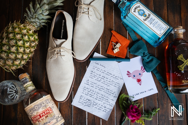 Wedding details in Curacao showcase shoes, drinks, and personal items on a wooden table