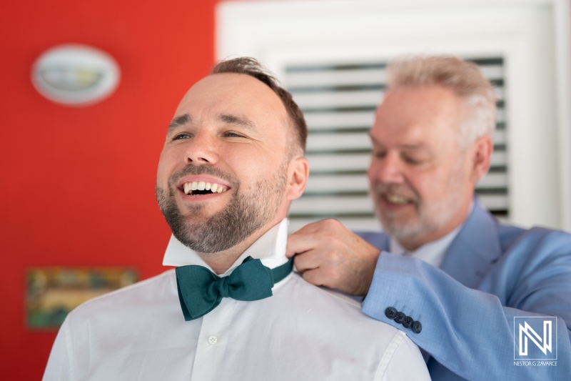 Groom getting ready for a wedding in Curacao with help from a friend