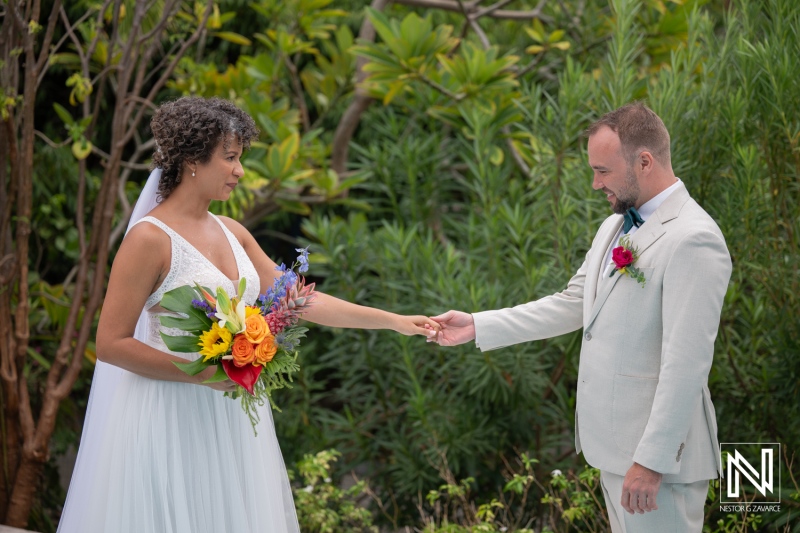Couple exchanges vows during wedding ceremony in Curacao outside with tropical plants in the background