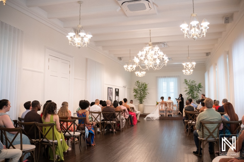 Wedding ceremony in Curacao takes place in a beautiful indoor venue with guests seated and couple in focus