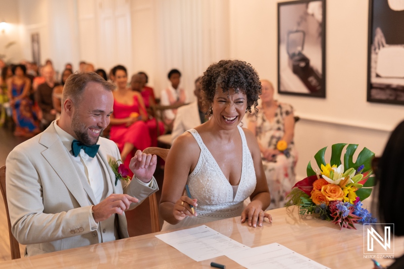 Couple signs wedding documents at a ceremony in Curacao with guests in attendance celebrating the occasion