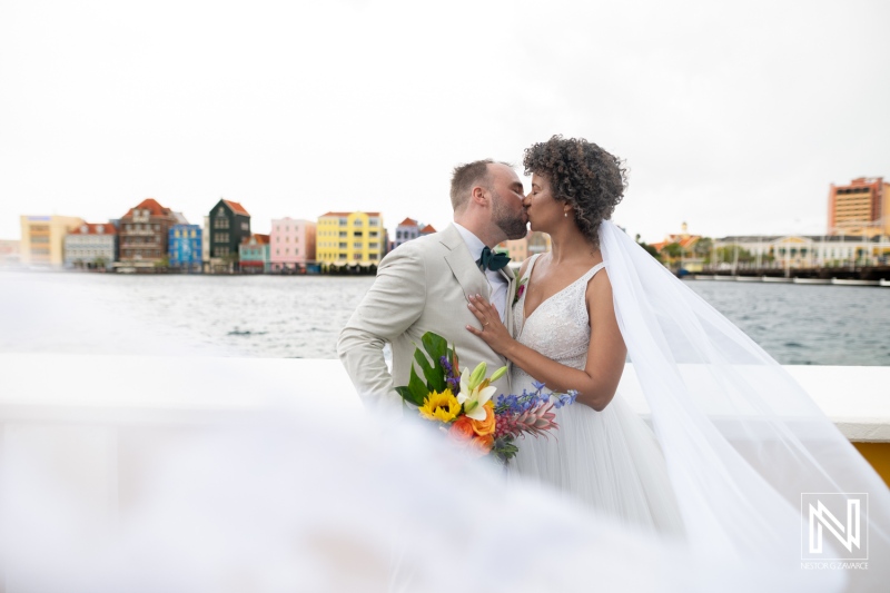 Couple shares a kiss during wedding ceremony in Curacao by the colorful buildings near the water