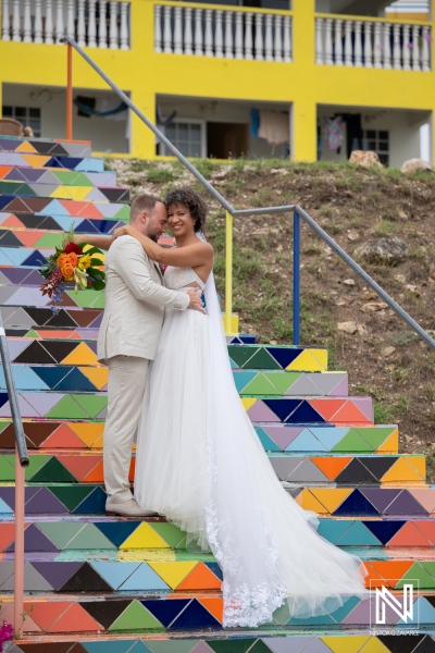 Couple shares a moment on colorful steps during their wedding in Curacao near bright buildings