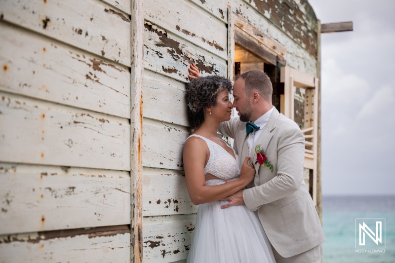 Couple shares moments during wedding in Curacao near the beach with simple wooden structure in the background