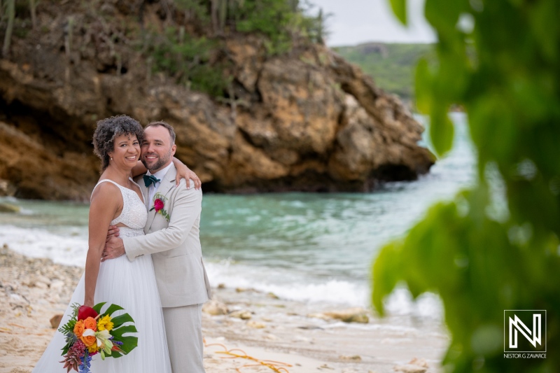 Couple celebrates wedding on beach in Curacao with joyful smiles and bright flowers