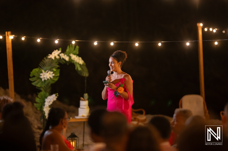 Wedding celebration in Curacao with a guest giving a speech under string lights in the evening