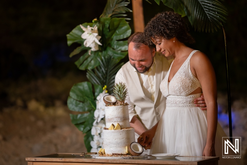 Couple cuts wedding cake during ceremony in Curacao with guests celebrating their special day