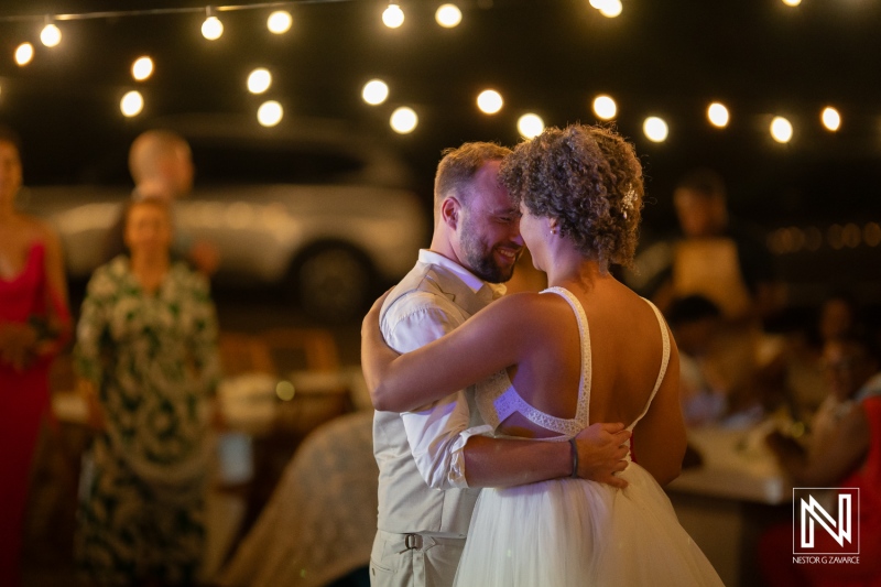 Couple dances at their wedding celebration in Curacao under string lights in the evening